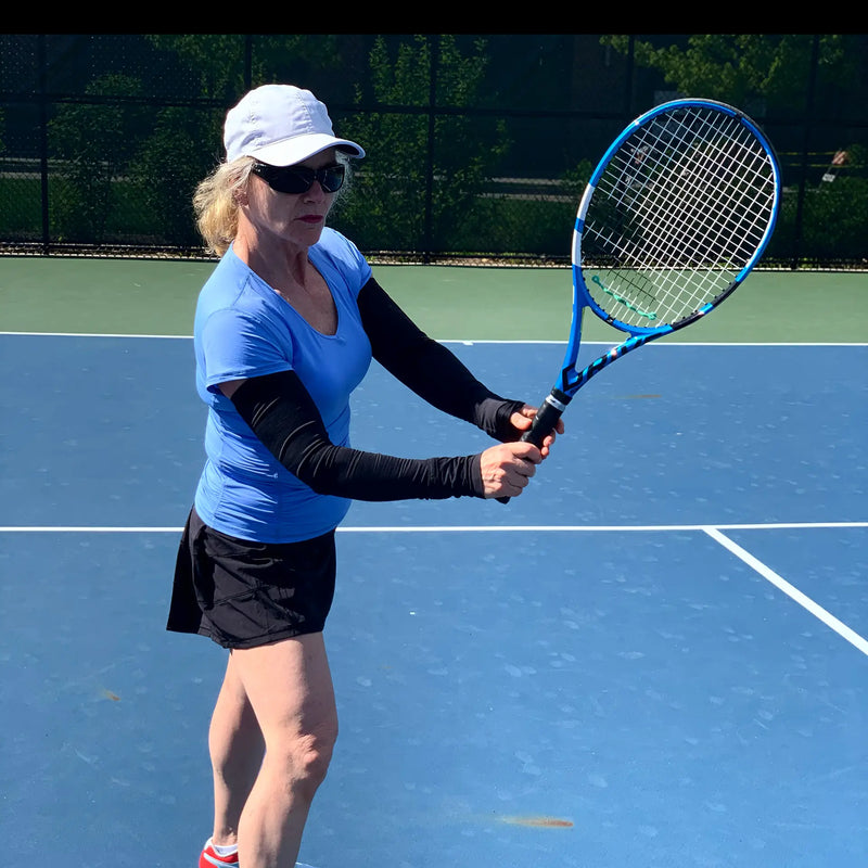woman playing tennis while wearing sun protection sleeves from Belesun apparel