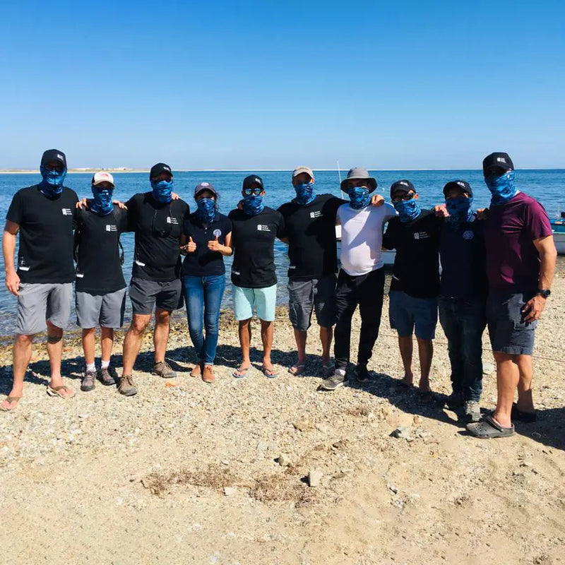 large group of friends posing on the beach weating sun protection neck gaiters